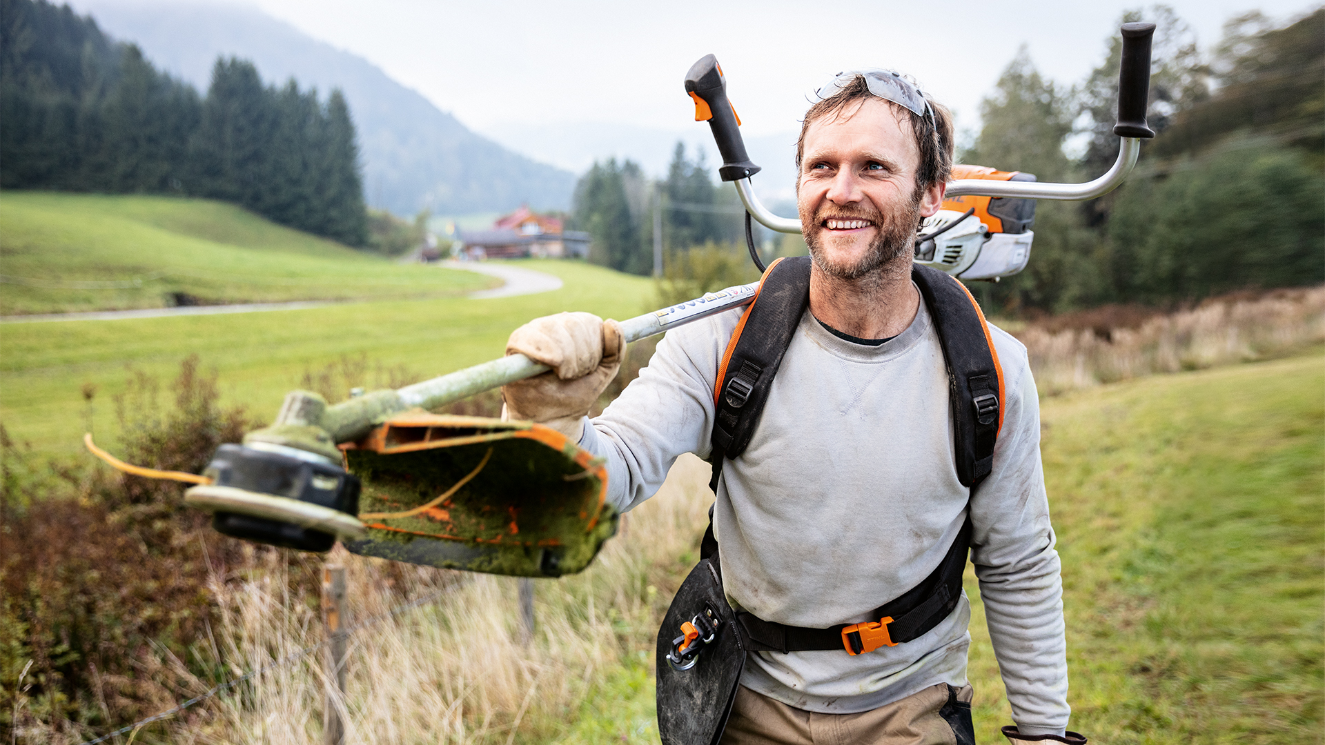 Un homme avec une débroussailleuse STIHL et un harnais universel Advance PLUS dans un pré