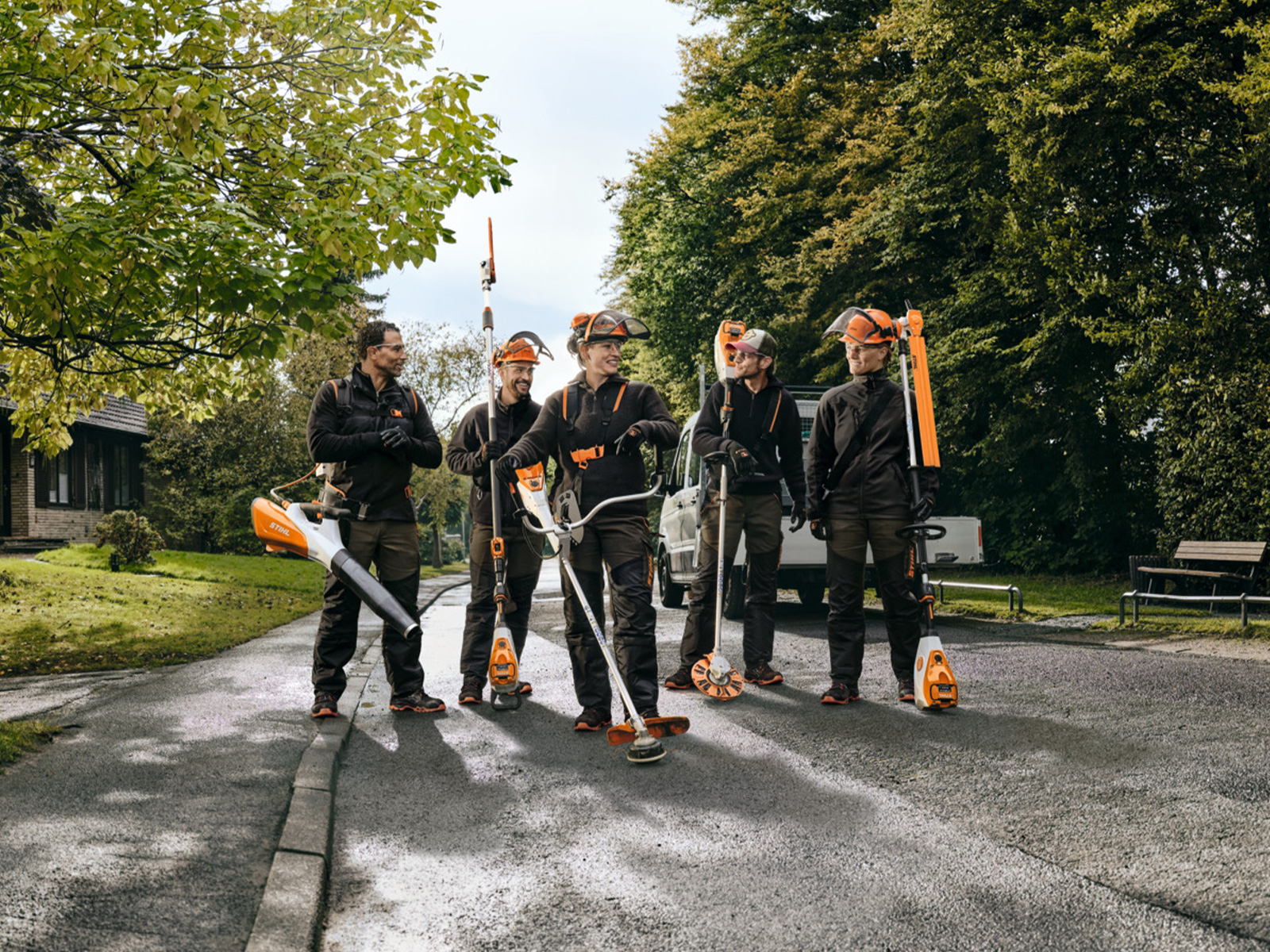 Cinq personnes en équipement de protection au travail avec des outils à batterie STIHL sur une route