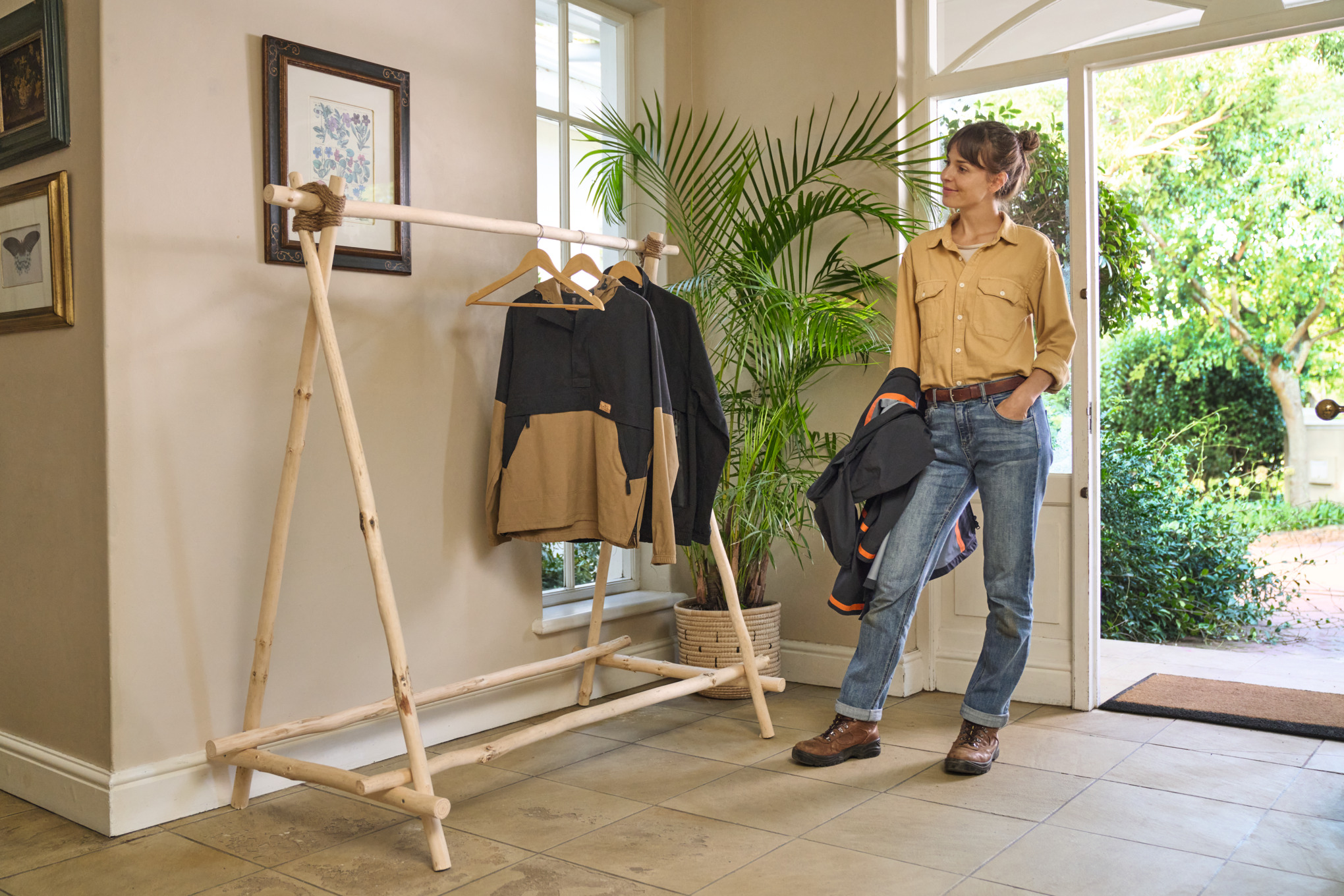 Femme souriante devant un portant à vêtements en bois qu’elle a fabriqué elle-même