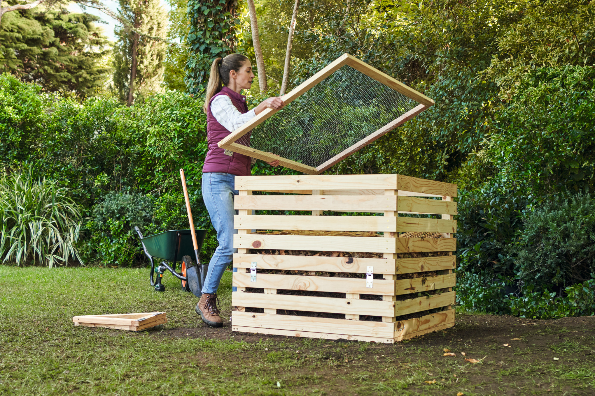 Une femme dans un jardin recouvre un bac à compost qu’elle a construit elle-même