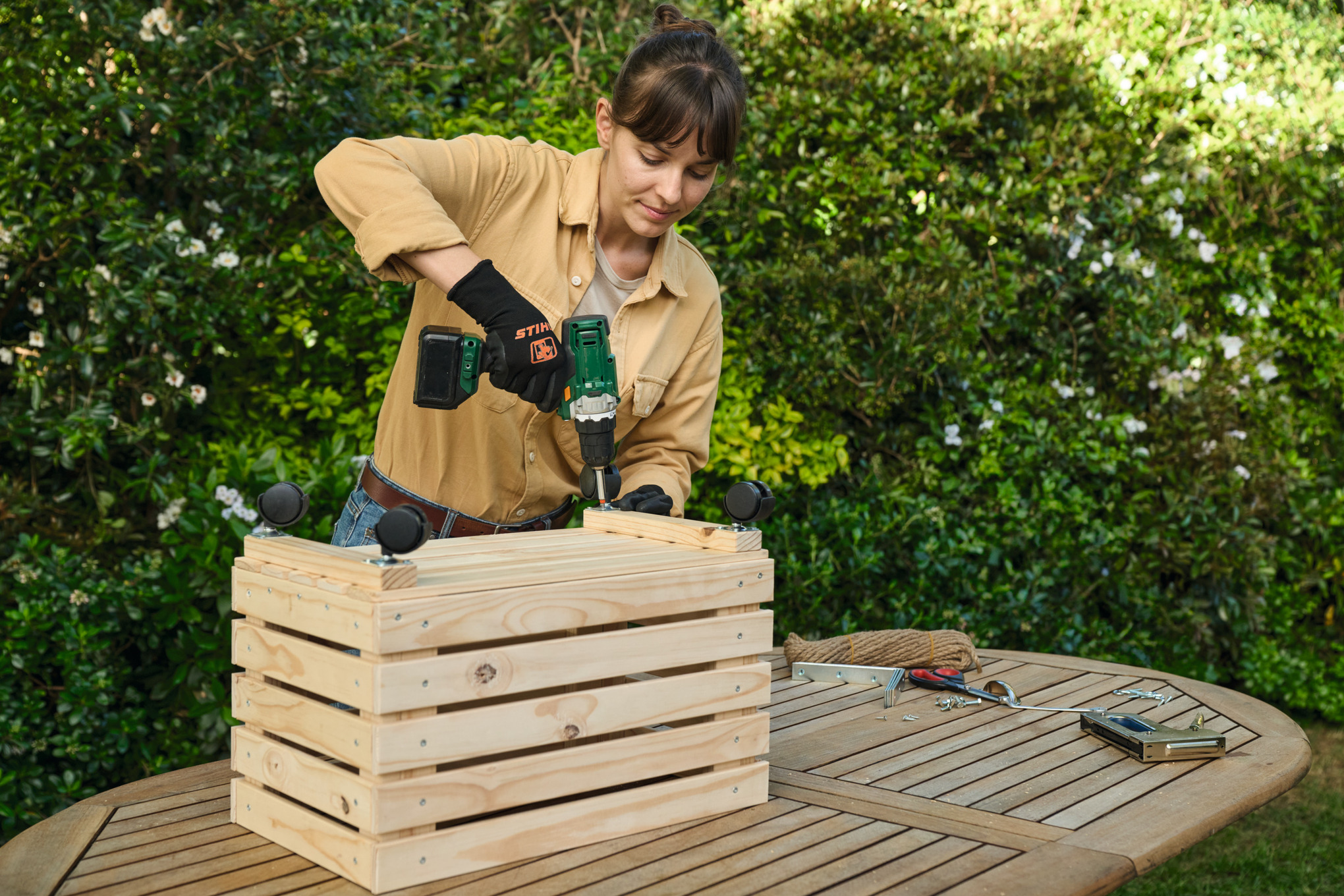 Femme vissant des roulettes pour meubles sur sa jardinière