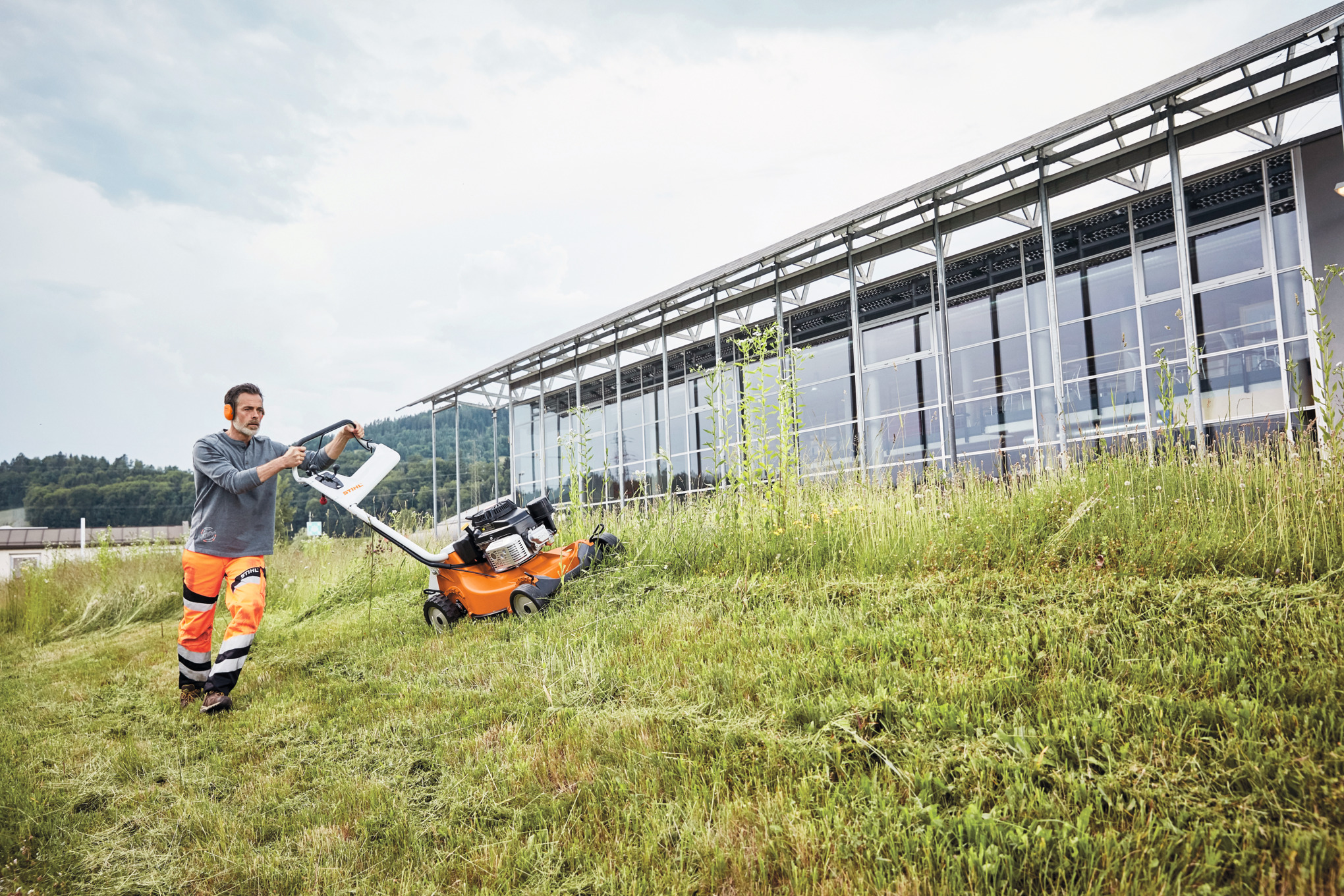 Un homme en train de tondre en pente avec une tondeuse à gazon à essence STIHL&nbsp;RM&nbsp;756&nbsp;GC 