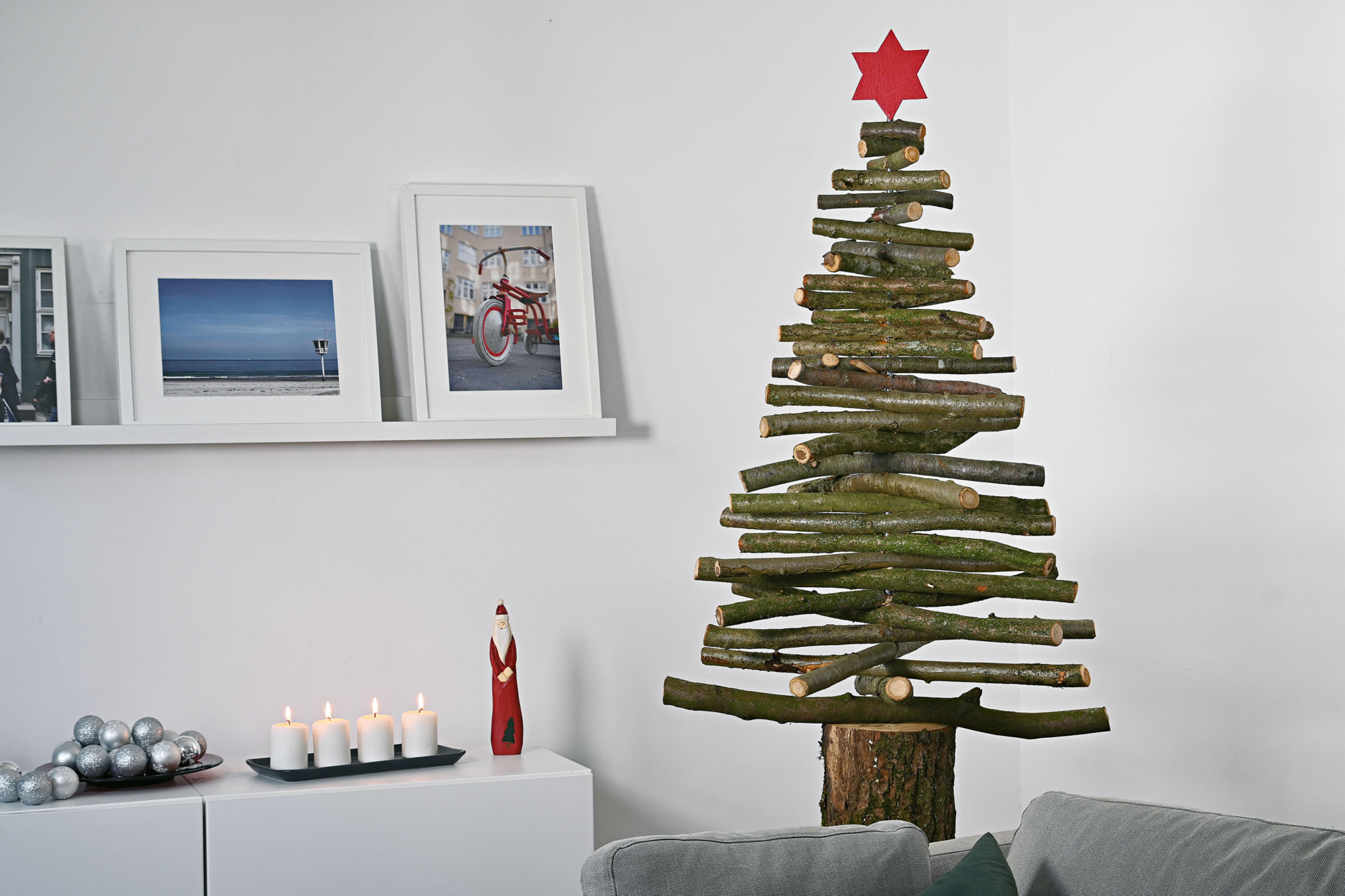 Sapin de Noël fait maison avec des branches en bois et une étoile rouge sur la pointe dans un intérieur décoré pour Noël