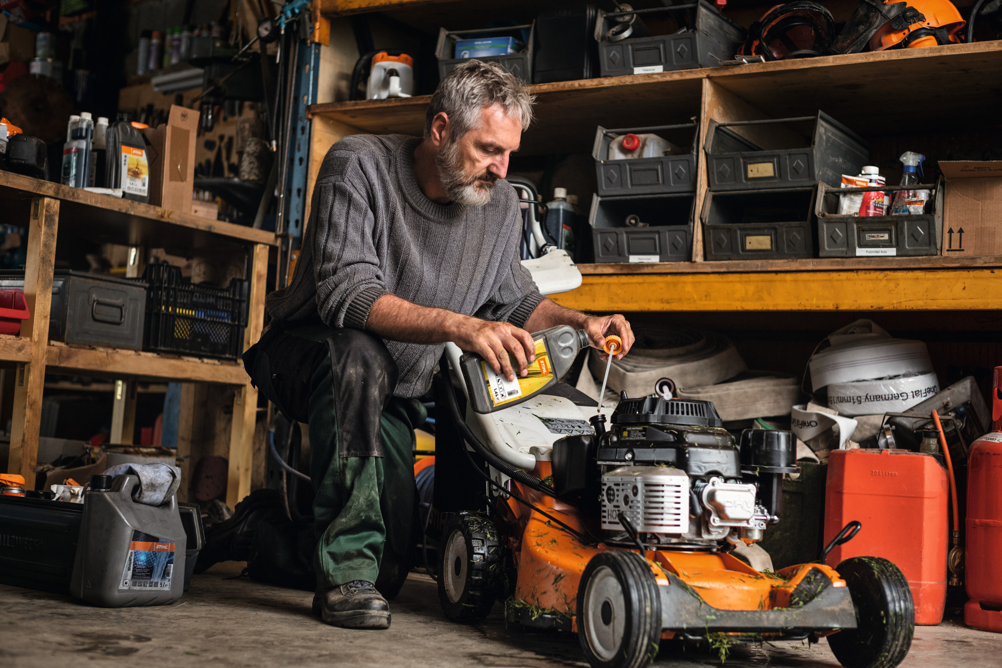 Un homme entretient sa tondeuse thermique STIHL RM 756 dans son garage