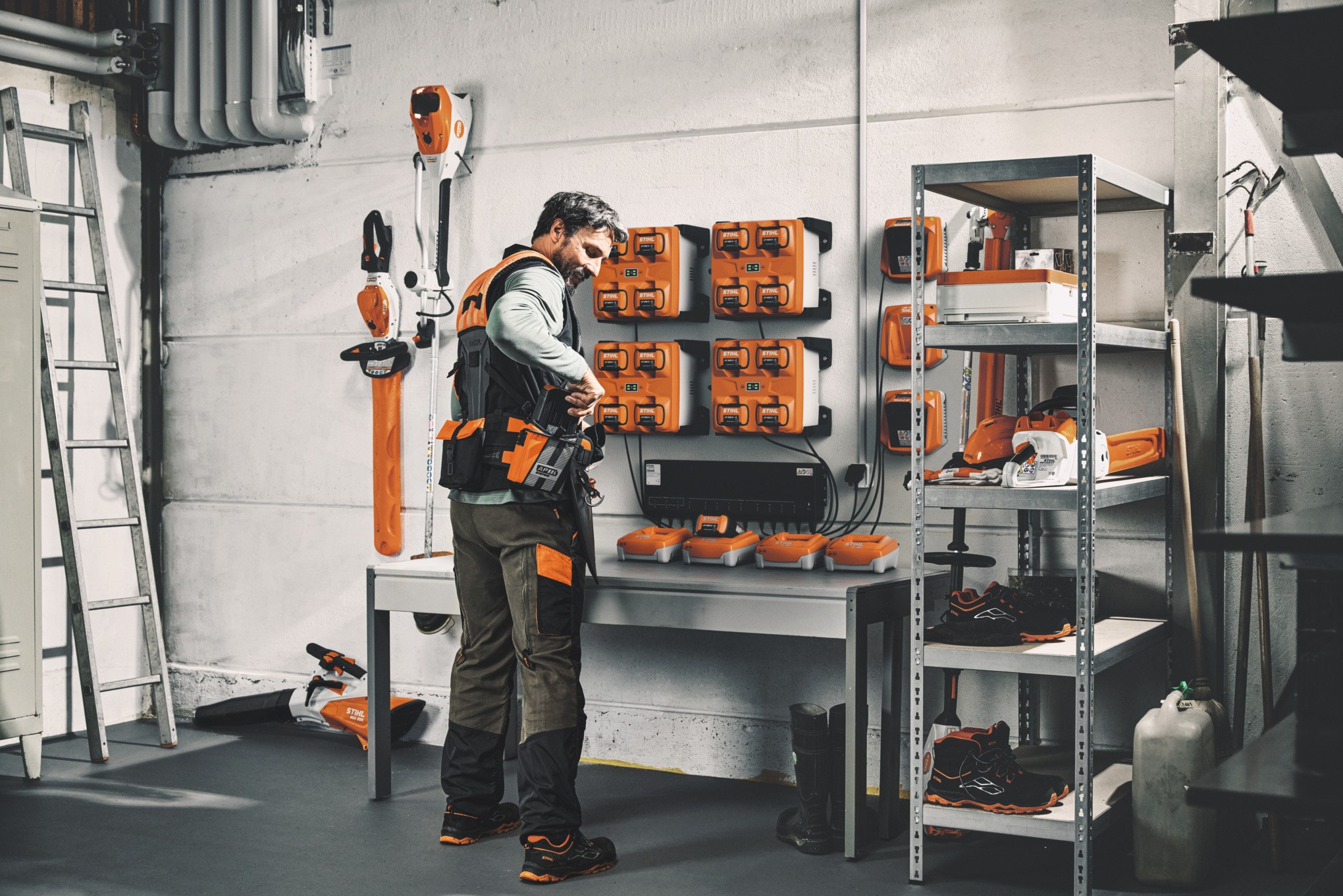 Un homme dans un atelier prépare son système de ceinture modulaire ADVANCE X-Flex avec des batteries chargées grâce à la solution de charge CM 12.