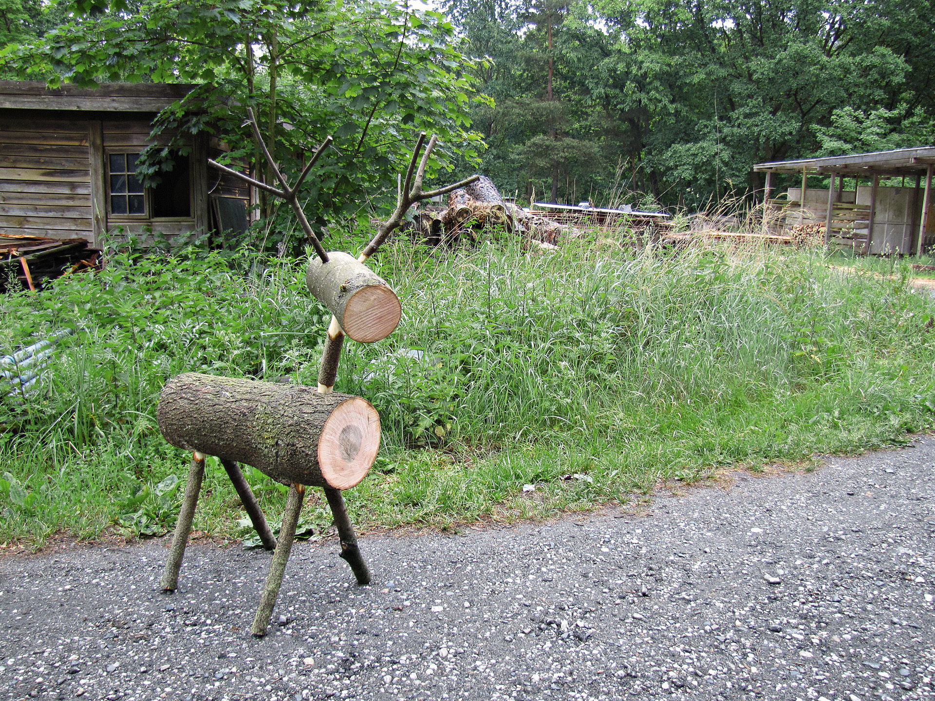 Renne en rondins de bois bricolé devant de l’herbe et une cabane
