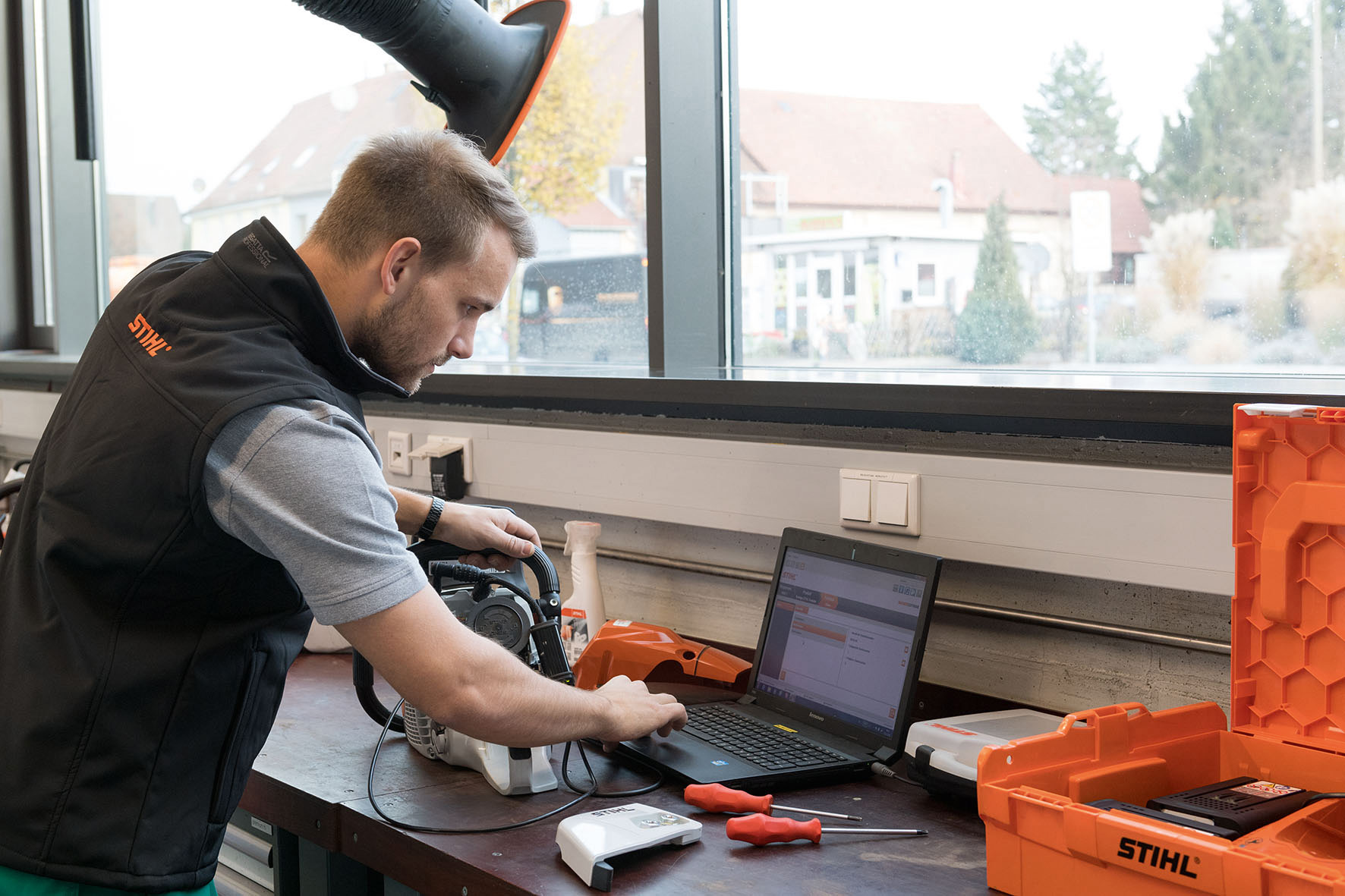 Un homme sur son ordinateur portable avec une tronçonneuse à ses côtés.