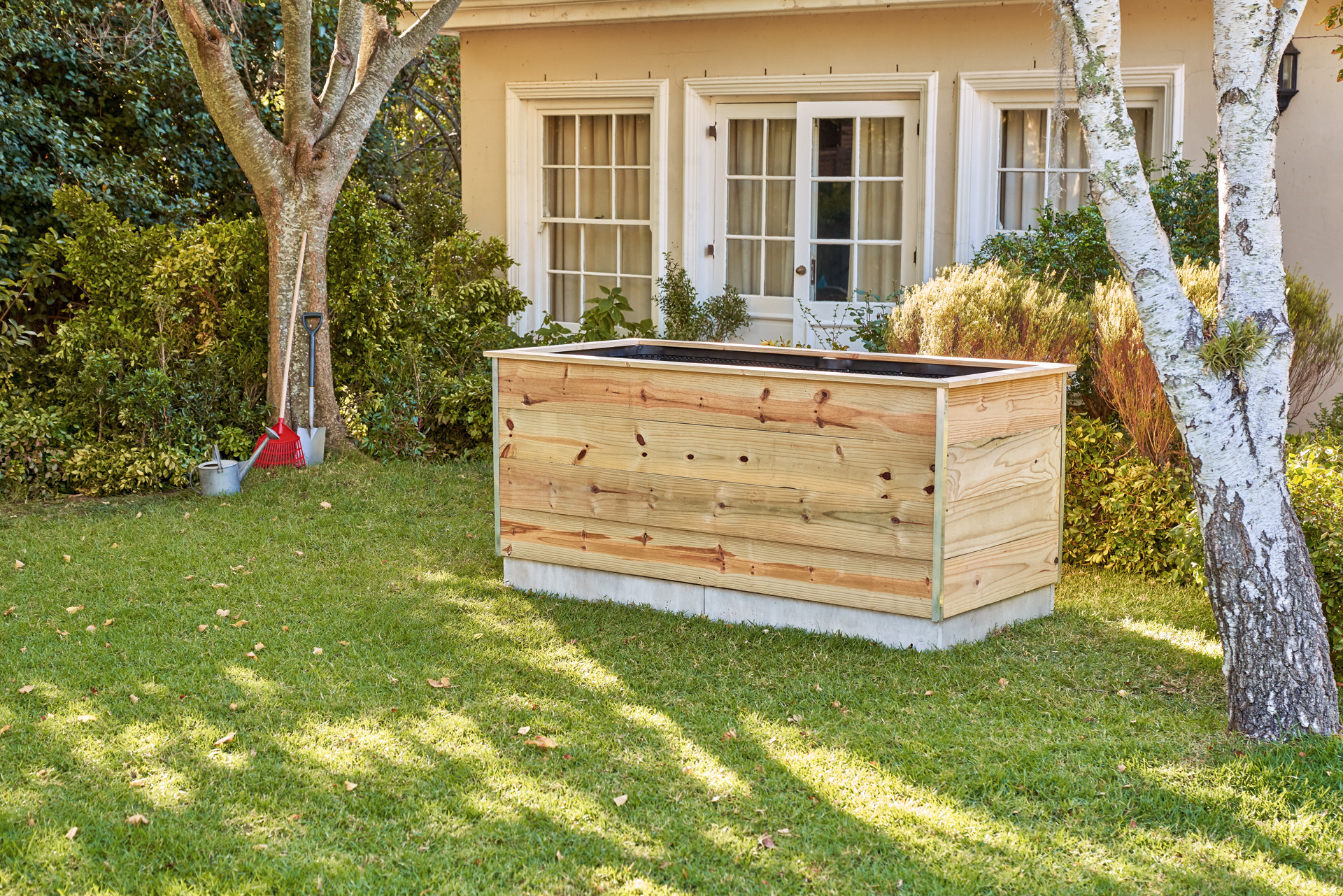 Un grand potager en planches de bois dans un jardin devant une maison