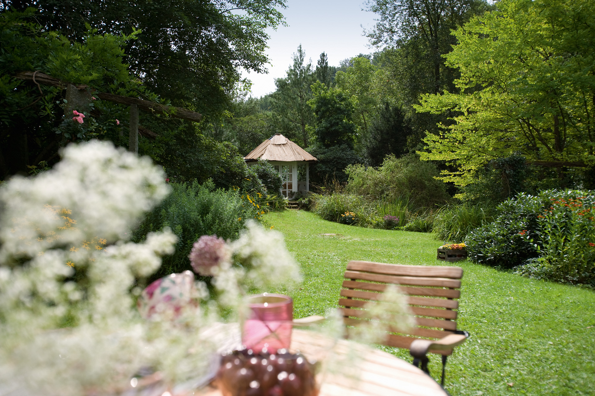 Vue d’un jardin avec pelouse au premier plan et cabane au fond 