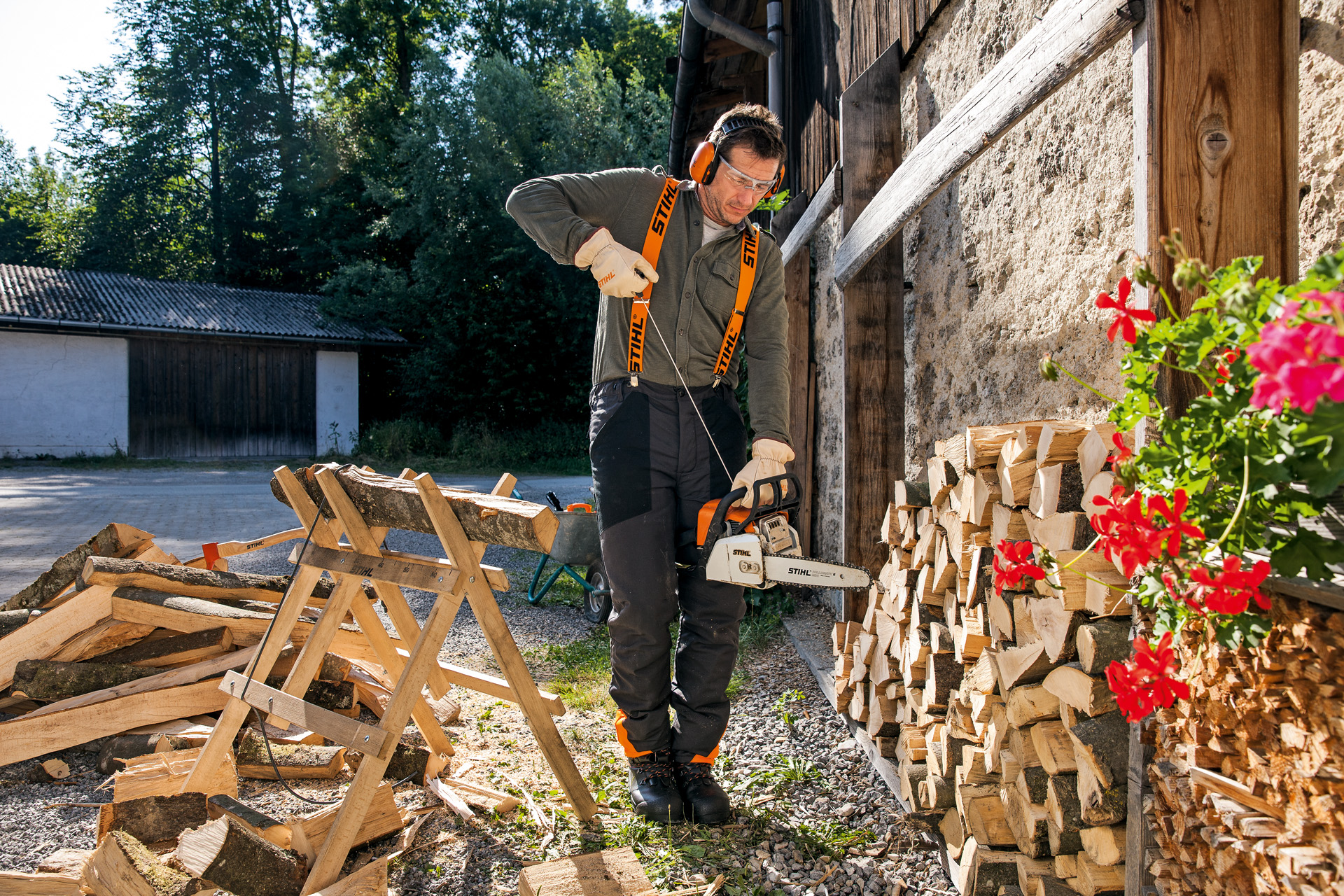 Un homme en tenue de protection tenant une tronçonneuse thermique STIHL équipée d’ElastoStart et d’un guide-chaîne Light 04