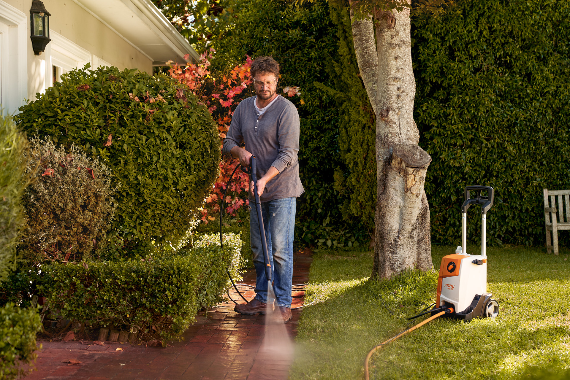 Un homme nettoyant le pavage devant sa maison avec un nettoyeur haute pression STIHL RE 110 
