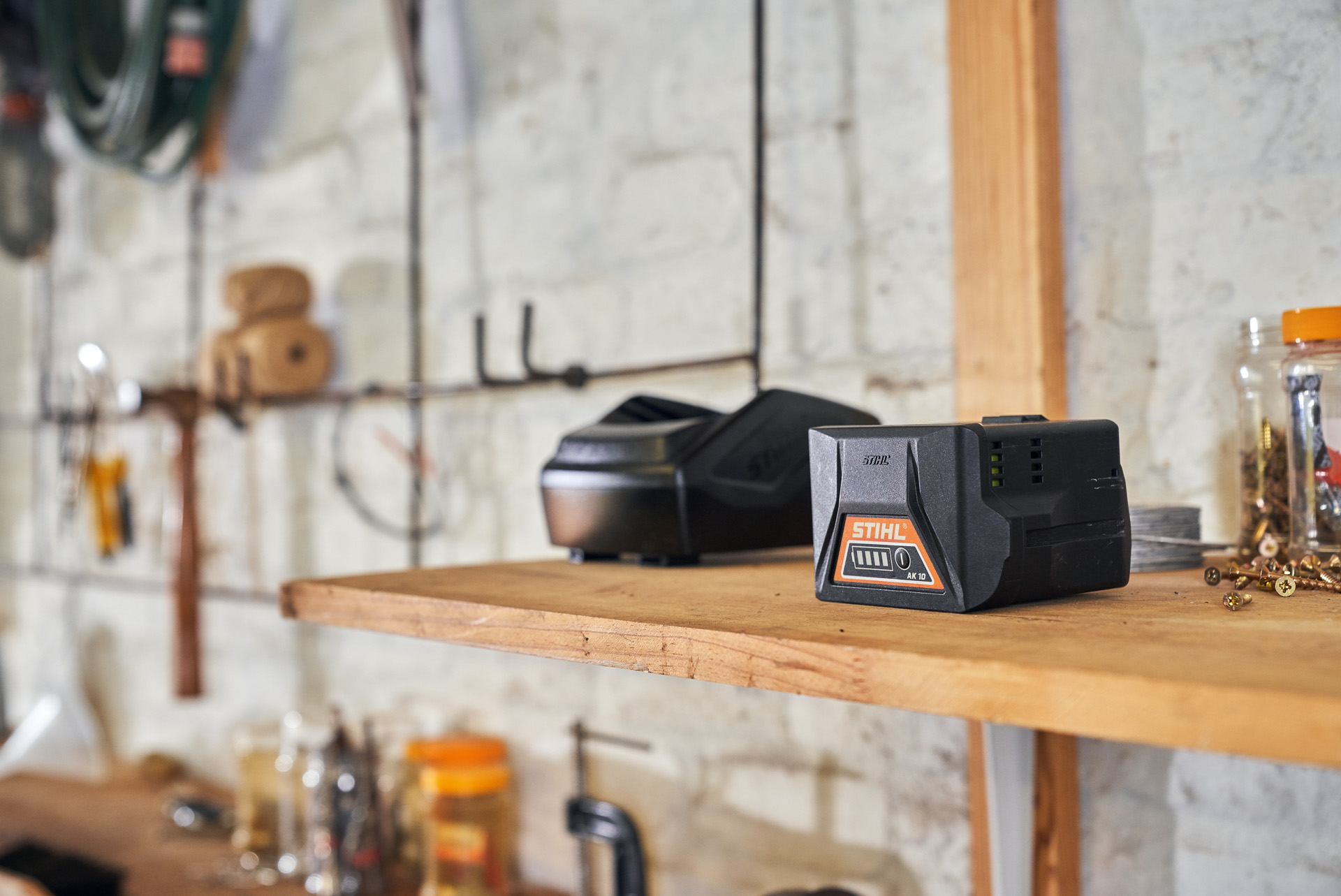 Un chargeur et une batterie STIHL sur une étagère en bois dans un atelier  Crédit photo
