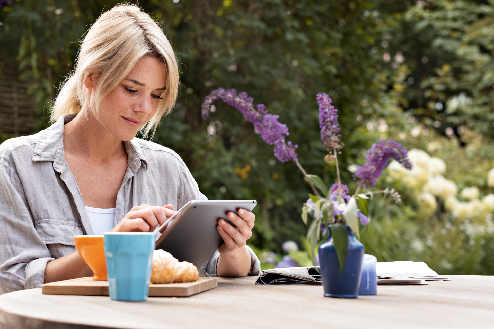 Femme utilisant une tablette sur une table dans le jardin