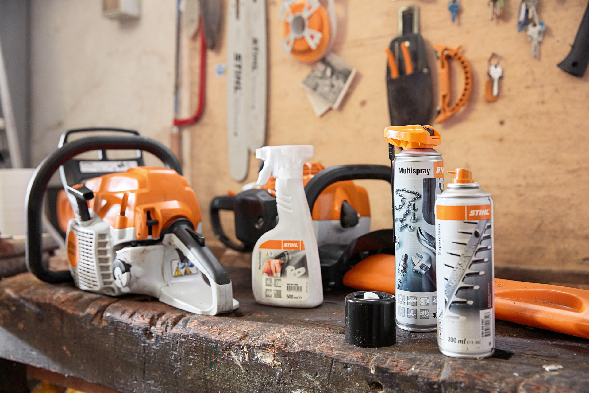 Plusieurs produits STIHL sur un établi : une tronçonneuse, Varioclean, Multispray et le solvant pour résine Superclean