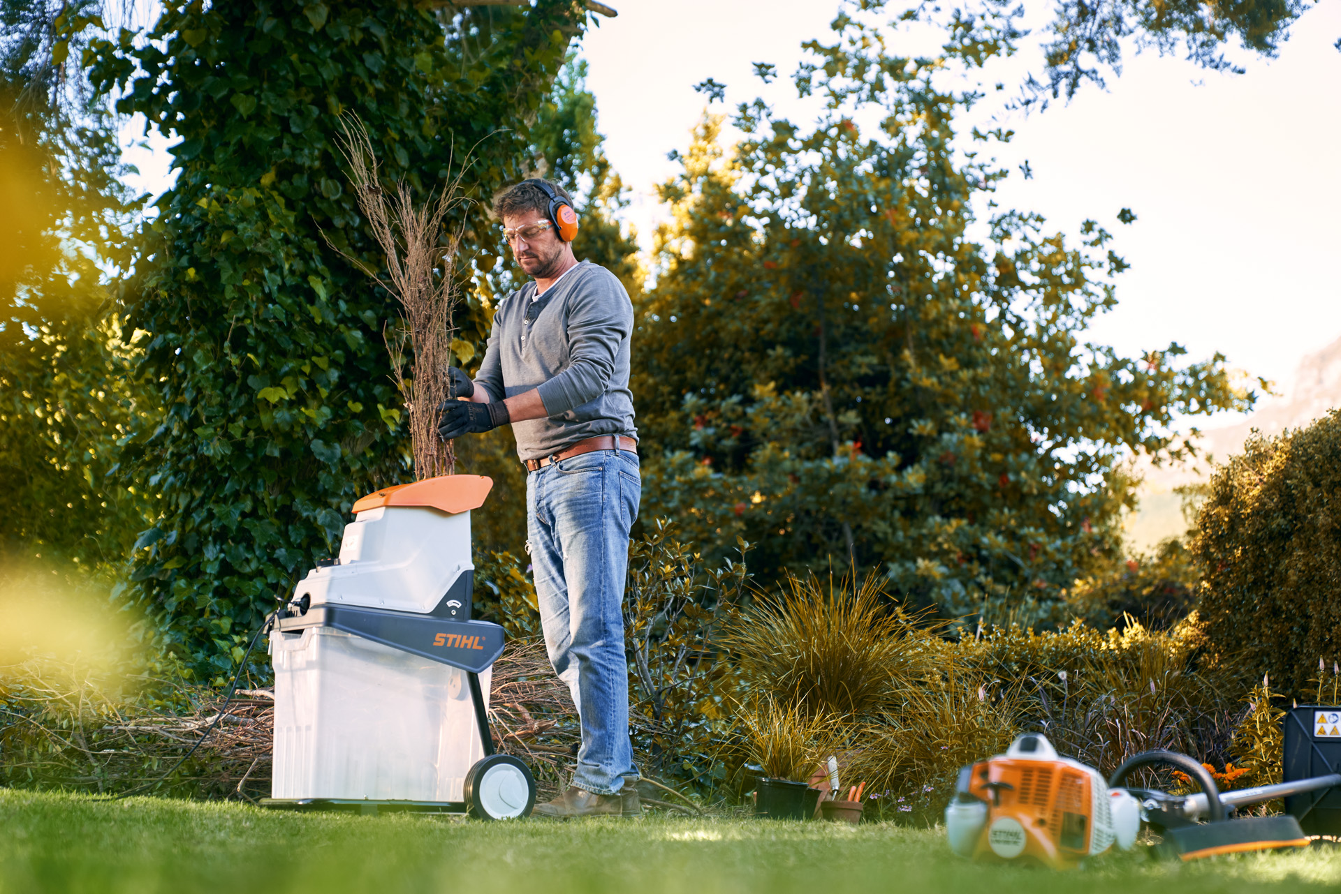 Un homme équipé d’une protection auditive utilisant un broyeur électrique STIHL GHE 140 L dans un jardin