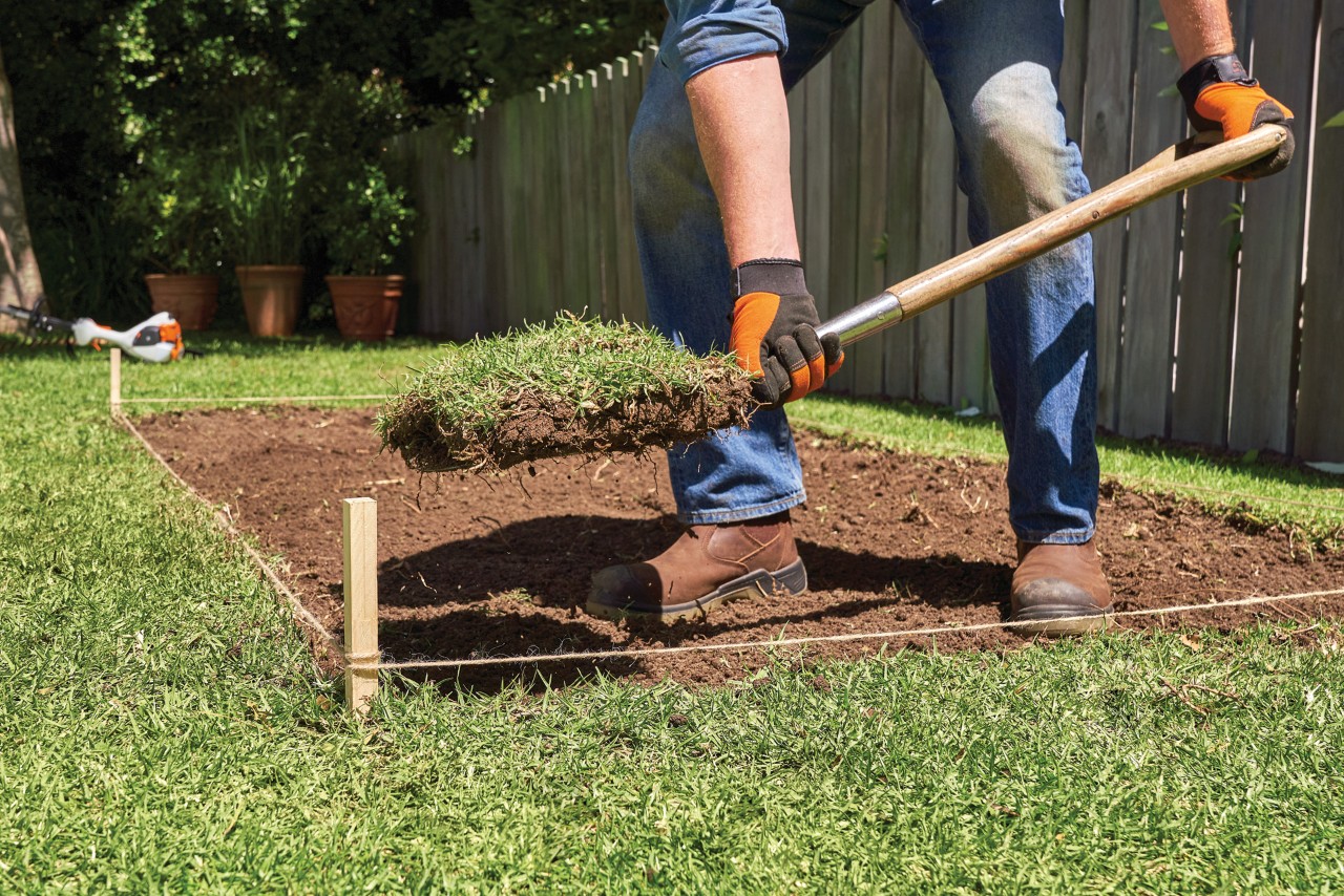 Un homme prépare le sol pour accueillir un potager