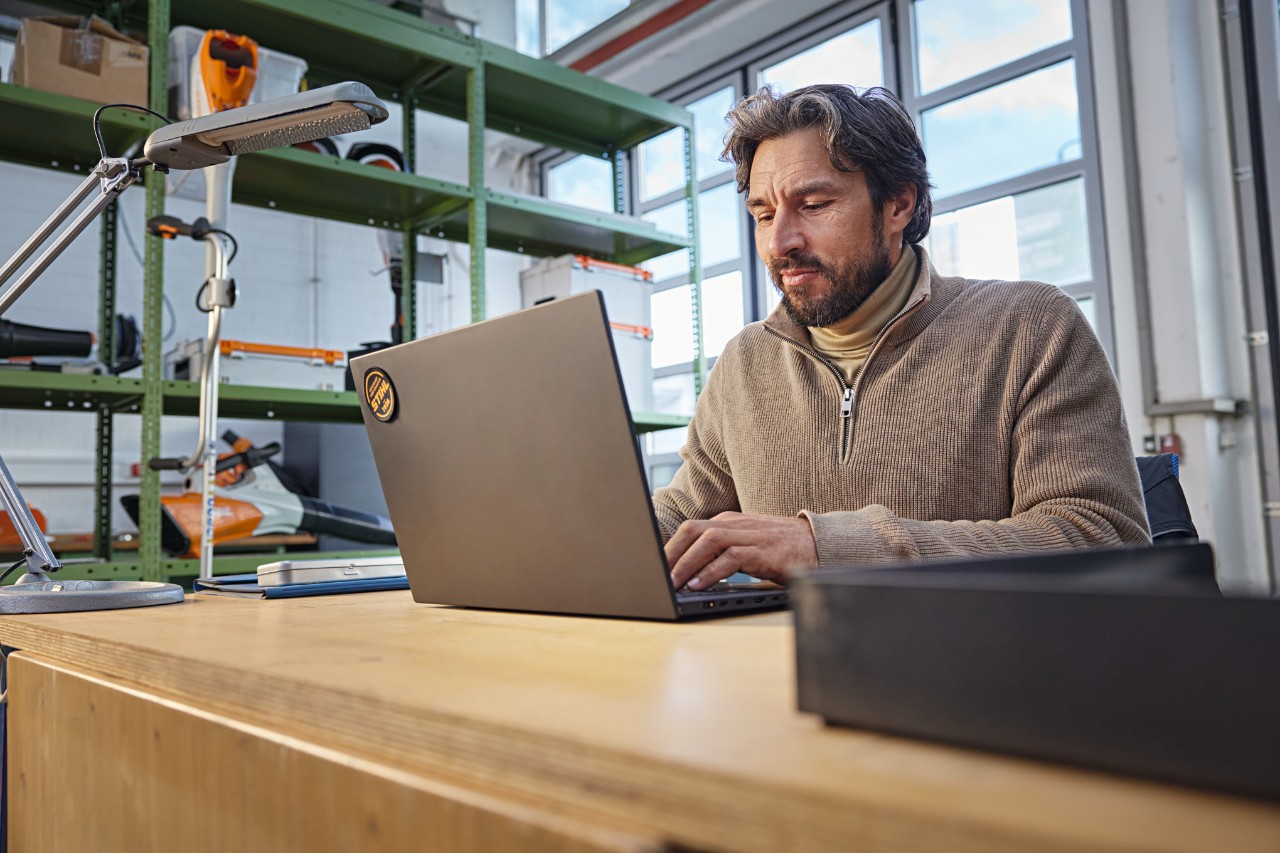 Une personne est assise à un bureau dans un atelier avec un ordinateur portable.