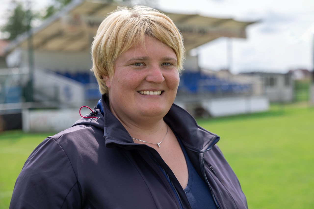 Lesly Huber, intendante de terrain, se trouve sur le terrain de sport SC Sand et sourit à la caméra