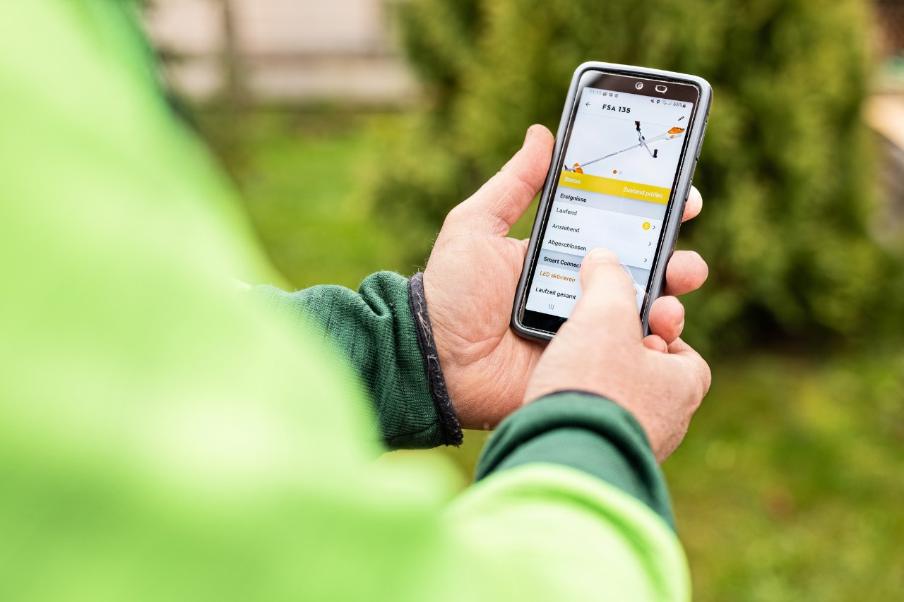 Gros plan sur la manière dont une personne utilise l’application STIHL connected sur son smartphone