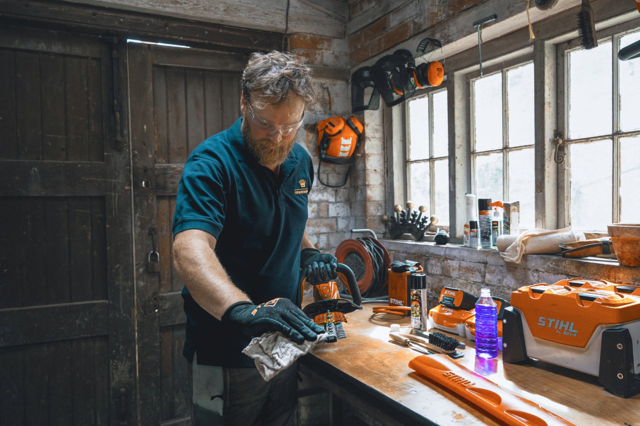 Un homme dans un atelier essuyant un taille-haies STIHL avec un chiffon