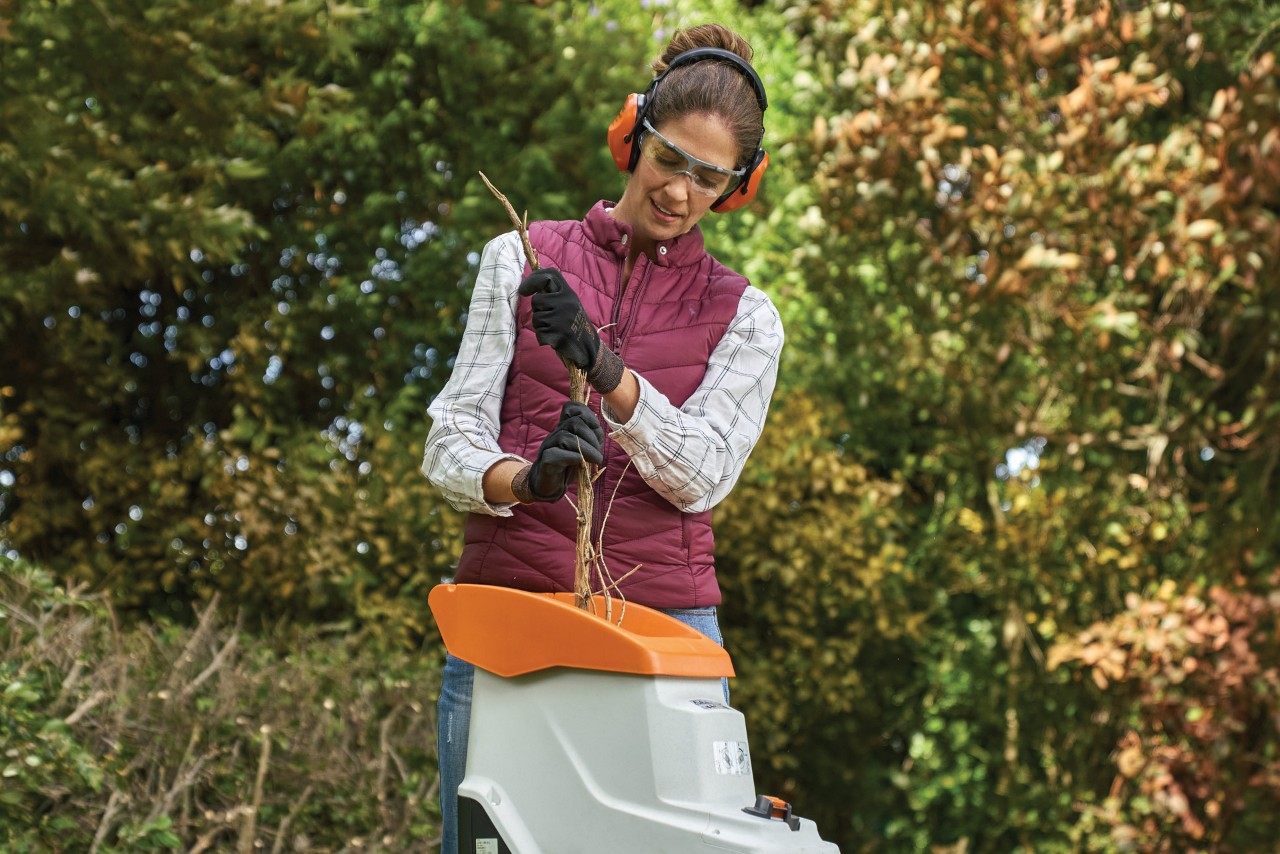 Une femme portant un casque anti-bruit lors du broyage de végétaux