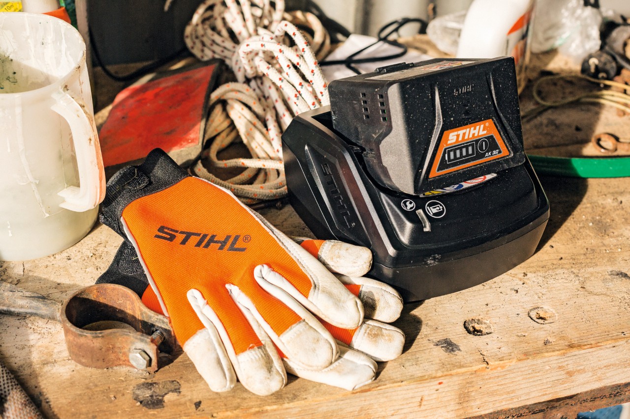 Batterie et gants posés sur un plan de travail