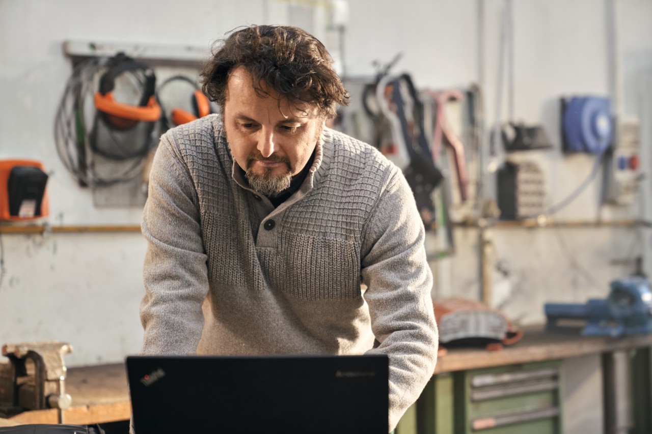 Un homme utilise un ordinateur portable dans un atelier.