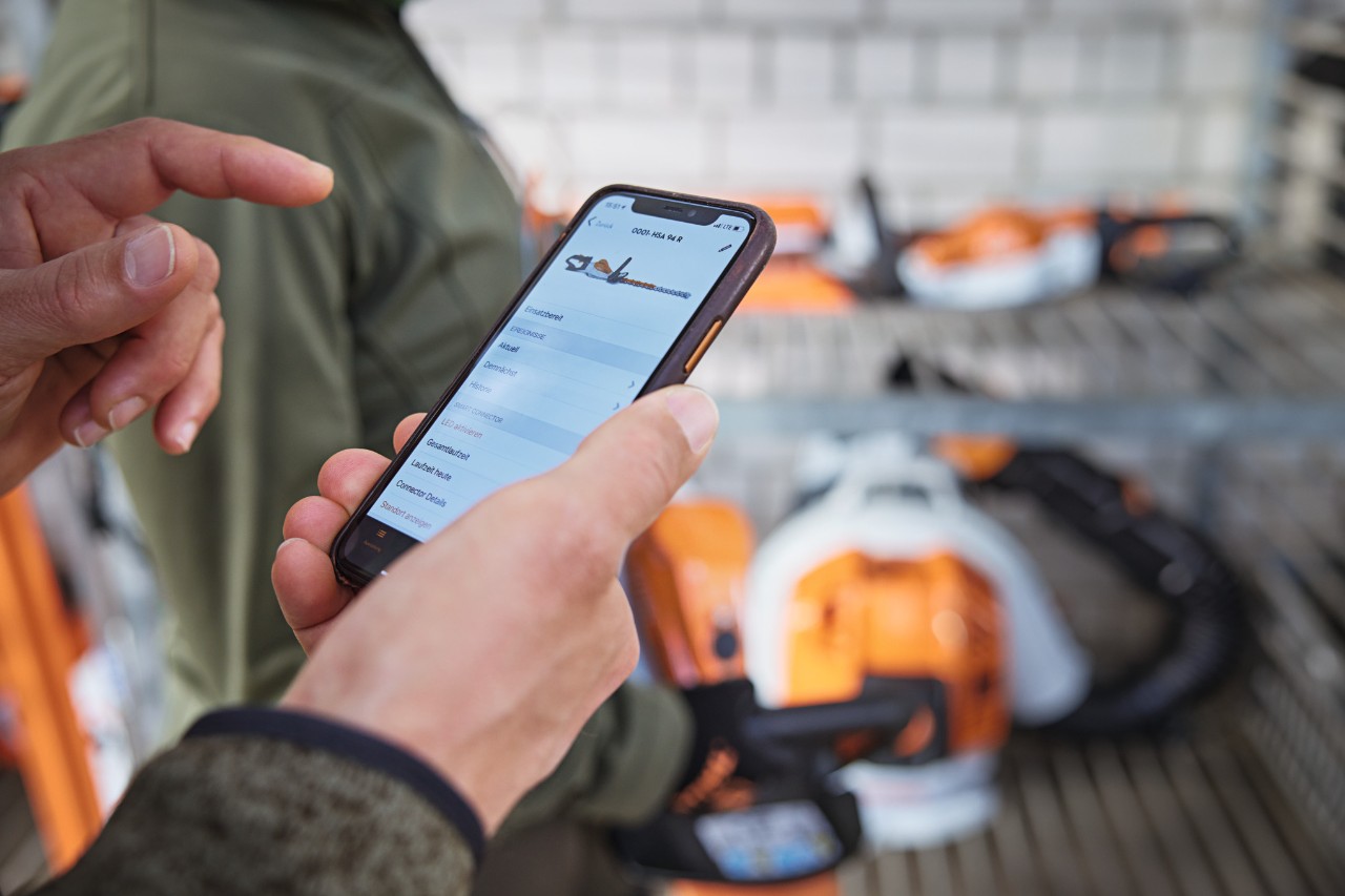 Person im Lager prüft Datum in der STIHL connected App auf dem Smartphone