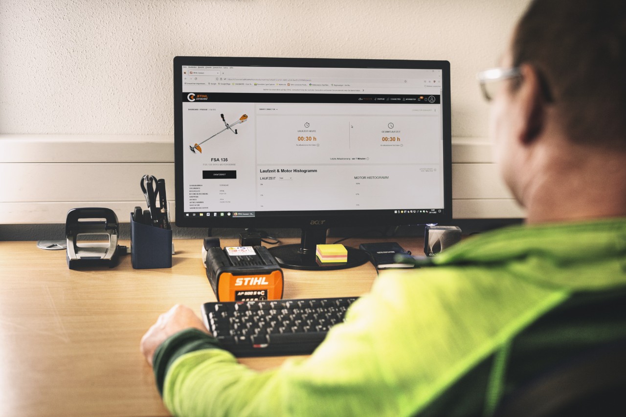 L'homme est assis devant son ordinateur et travaille avec le portail connecté STIHL