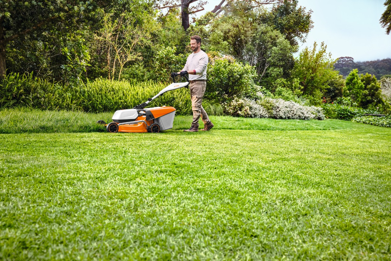 Un homme coupe l'herbe avec une tondeuse à batterie