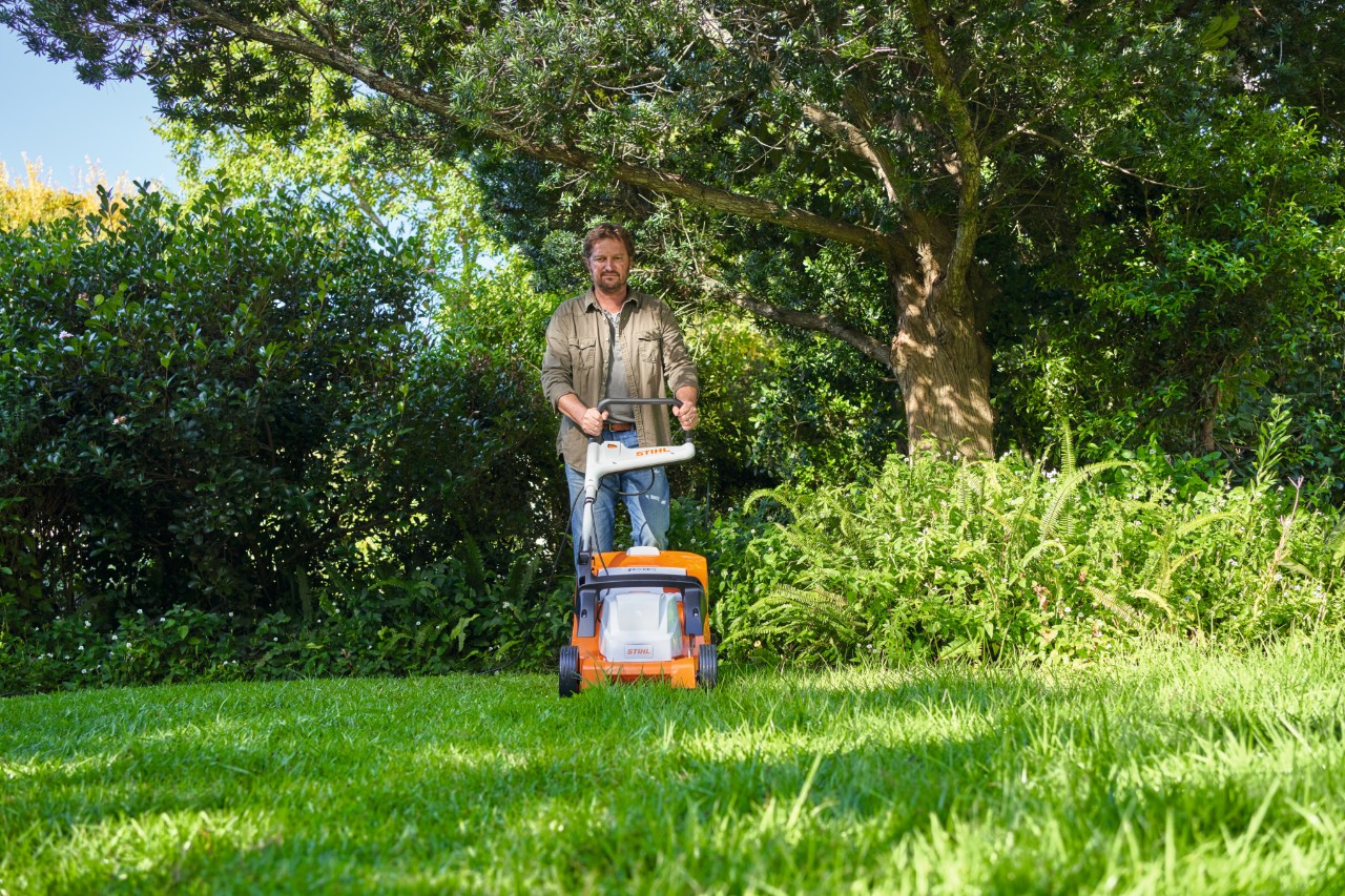 Un homme coupe l'herbe avec une tondeuse électrique