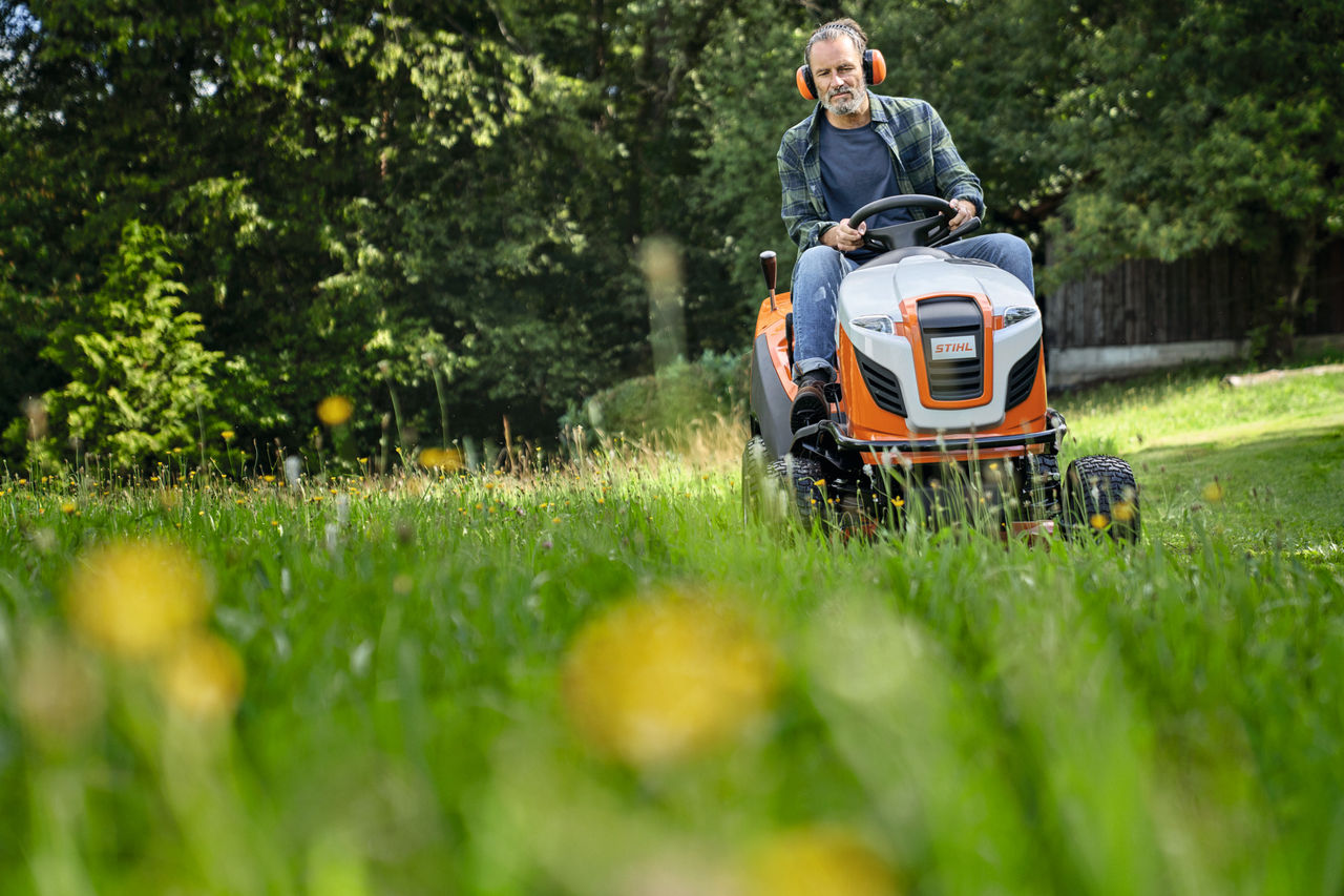 Un homme tond la pelouse avec un tracteur tondeuse