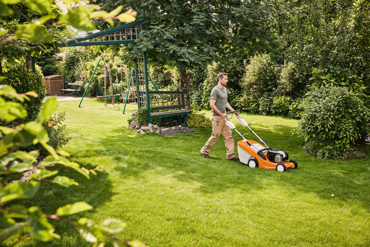Un homme coupe l'herbe avec une tondeuse à essence